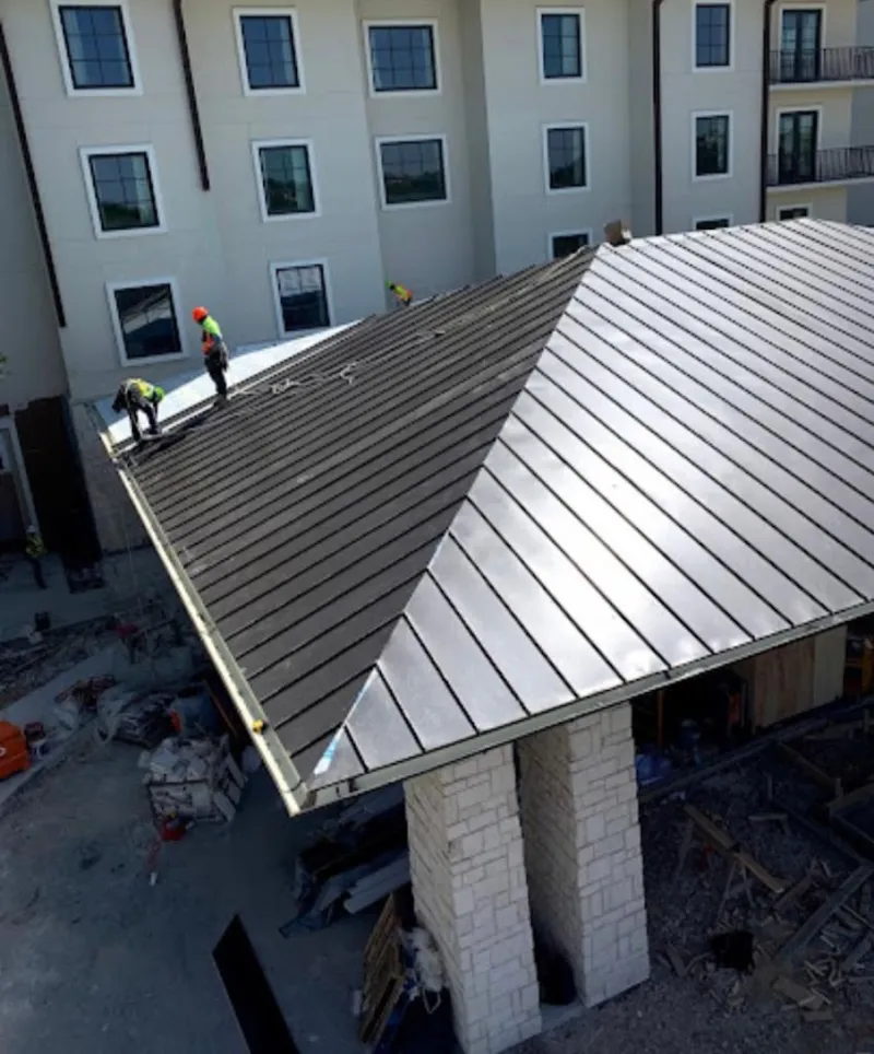 Crew installing standing seam metal roof panels on a commercial project in Petal